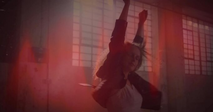 Dancer raising arms shoulder-high triggers red waveform while spinning glowing batons for tech demo