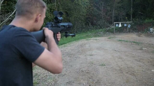Young male target practicing outdoors with firearms 