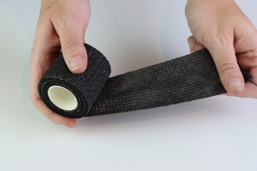 Black cohesive bandage beeing stretched