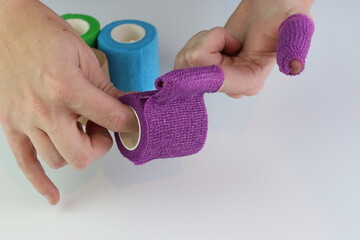 Woman wrapping a purple cohesive bandage in the fingers