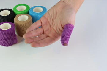 Woman wrapping a purple cohesive bandage in the fingers
