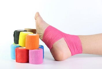 Woman foot with a pink cohesive bandage wrapped in the ankle isolated in a white background