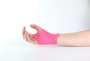 Woman hand with a pink cohesive bandage isolated in a white background