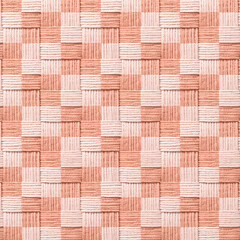 Close up view of a woven textile in a checkerboard pattern showcasing textured threads in soft peach and cream colors creating a warm and inviting design.