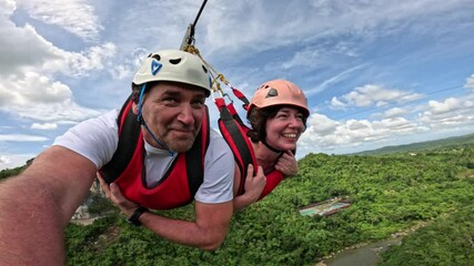 Smiling couple enjoying thrilling zipline ride over scenic jungle on Bohol island Couple flying together on Superman zipline above green tropical forest in Bohol, Philippines - Powered by Adobe