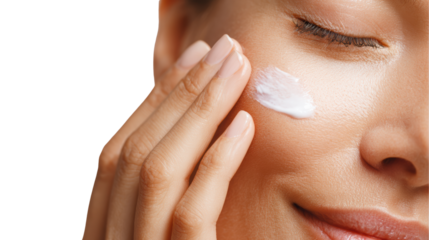 Woman applying moisturizer on her face, showcasing a skincare routine and healthy skin.