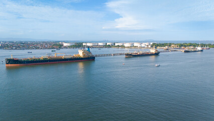 Oil tanker docked at Cilacap refinery with large storage tanks, suitable for energy industry websites, transportation logistics, and education resources.