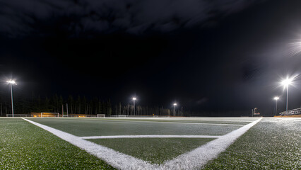 Empty sports field under glowing perimeter lights at night, a serene and modern athletic atmosphere.