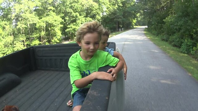 Young boys riding in back of truck in summer 