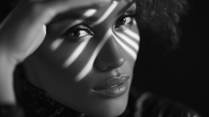 Black and white portrait of a woman with dramatic lighting casting striped shadows across her face, highlighting her eyes and expression.