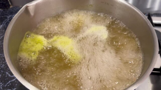 A vegetable bouillon cube dissolving in a pot of boiling water