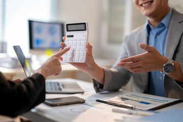 A man is holding a calculator and pointing to a number on it