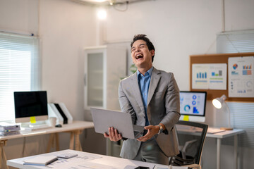 A man in a suit is smiling and holding a laptop
