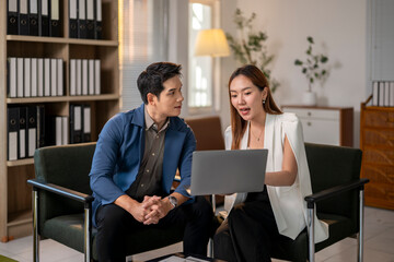 The man is looking at the laptop while the woman is looking at him