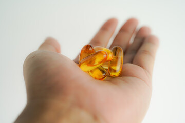 Male hand holding Fish oil capsules with omega 3, omega 9, vitamin D, vitamin E, Cod liver oil