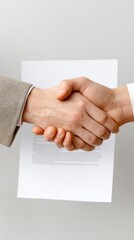 Two Hands Shaking Over a Formal Contract on a Light Background