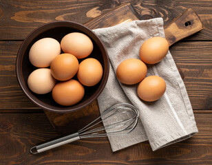 Breakfast Ingredients Still-Life: A rustic composition with a bowl overflowing with fresh, brown eggs next to a mixing tool and a cutting board, promising a culinary adventure.