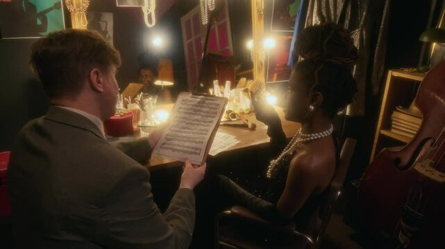 High angle shot of Black woman reviewing sheet music notes while preparing for show backstage in club
