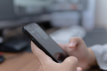 Close-up photograph of a person using a mobile phone with a blurred office background for technology and communication concepts
