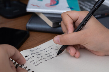 Close-up lifestyle photo of hand writing in a journal for study blog or creative project concept
