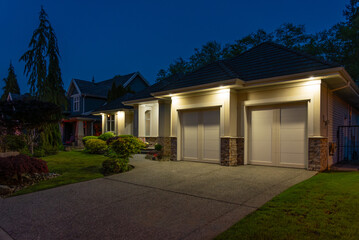 Garage door in luxury house with trees and nice landscape in Spring in Vancouver, Canada, North America. Night time on May 2025.