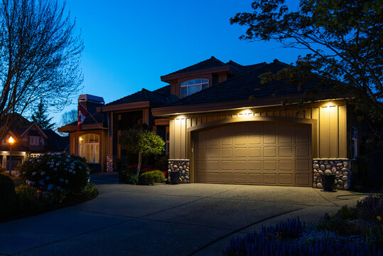 Garage door in luxury house with trees and nice landscape in Spring in Vancouver, Canada, North America. Night time on May 2025.