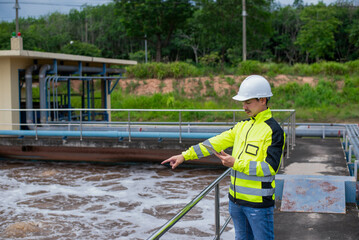 A wastewater treatment engineer is checking the treatment pond system to ensure that the water is clean and meets the standards.