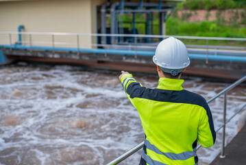 A wastewater treatment engineer is checking the treatment pond system to ensure that the water is clean and meets the standards.