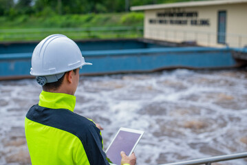 A wastewater treatment engineer is checking the treatment pond system to ensure that the water is clean and meets the standards.