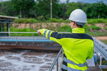 A wastewater treatment engineer is checking the treatment pond system to ensure that the water is clean and meets the standards.