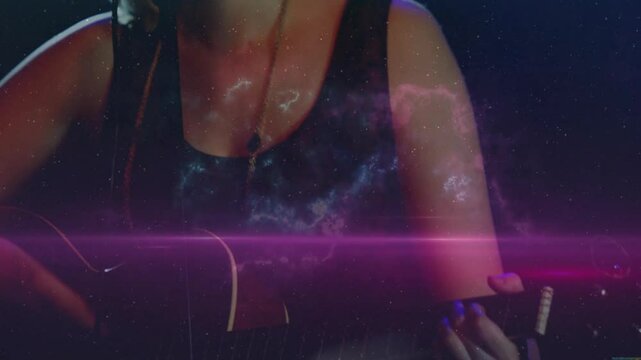 Female musician pressing guitar neck activating nebula while strumming singing for live music show