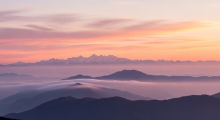 A scenic view of mountain ranges covered in fog under a pastel colored sky at dusk or dawn horizon