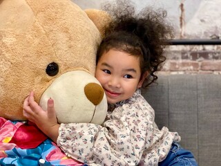 Little girl with a teddy bear in the living room at home