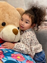 Little girl with a big teddy bear at home. Selective focus.