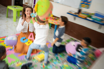 A preschool boy showing challenging behavior while a female teacher calmly interacts with him....