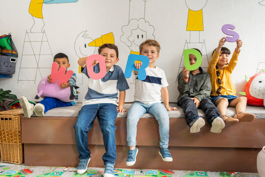 Diverse group of preschool children holding large colorful letters spelling “Words” in a bright classroom. Early language learning, playful literacy, preschool and kindergarten education