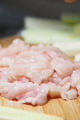 Freshly sliced chicken ready for cooking on a wooden board