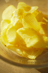 Crispy yellow potato chips in a clear bowl