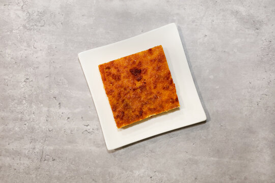 A piece of Mexican budin de pan con pasas (bread pudding with raisins) on a white dessert plate.