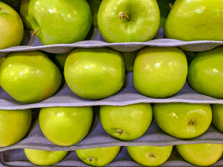 Granny smith apples stacked on packaging trays for protection. Green apples on display at the supermarket.
