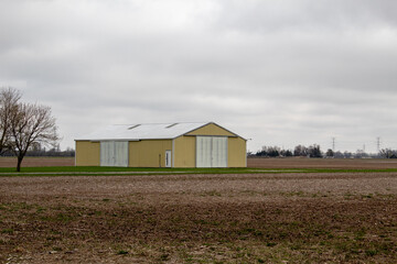 A yellow shed in the field. Farmland