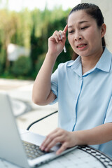 Young woman feeling overwhelmed and confused using laptop outside, struggling with online work, remote study, or digital communication issues under pressure, captured in realistic emotional scene.