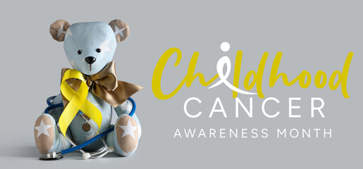 Teddy bear with yellow ribbon and stethoscope on grey background. Childhood cancer awareness concept