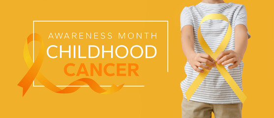 Little boy with childhood cancer awareness ribbon on yellow background