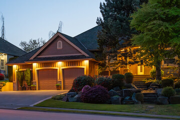 Two story stucco luxury house with nice Spring blossom landscape at night in Vancouver, Canada,...