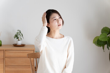 頭痛で頭を押さえる女性