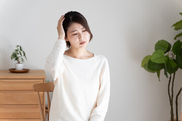 頭痛で頭を押さえる女性