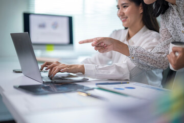 Two women are working on a laptop together