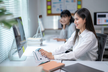 Fototapeta premium A woman is sitting at a desk with a computer and a keyboard