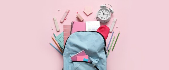 School backpack, alarm clock and stationery on pink background